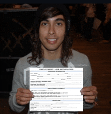 a man with long hair is holding up an employment application