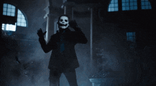 a man with a skull mask on his face is standing in a dark room