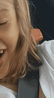 a close up of a woman 's face with a red item on her shoulder that says ' emergency exit ' on it