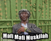 a man wearing a turban and a suit stands in front of a green fence with the words mafi mafi muskilah