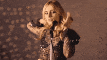 a woman is singing into a microphone while holding her hair
