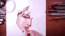 a drawing of a man 's face is on a table with colored pencils and pens