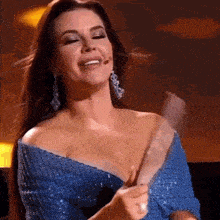a woman in a blue dress is smiling and holding something