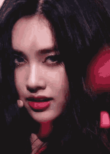 a close up of a woman 's face with long dark hair and red lips .