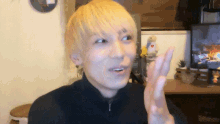 a man with blonde hair is making a peace sign in front of a tv