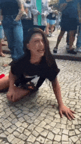 a woman is sitting on the ground with her legs crossed and a crowd behind her .
