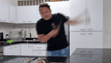 a man in a black shirt is standing in a kitchen with white cabinets
