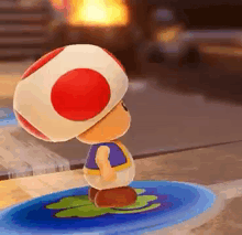 a toad with a red and white hat is standing on a blue leaf .