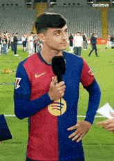 a man in a nike jersey is holding a microphone on a field