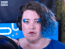 a woman with blue hair is wearing headphones in front of a video confidence coach logo