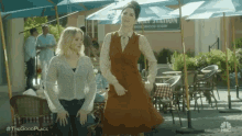 a couple of women are standing next to each other in front of a restaurant .