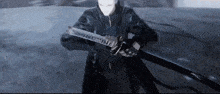 a man in a black jacket is holding a sword in his hands .