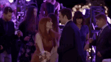 a man and a woman are dancing at a party with a crowd of people .