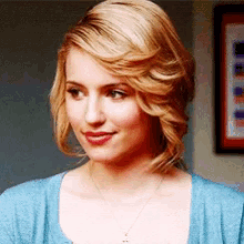 a close up of a woman 's face wearing a blue shirt and necklace .
