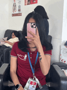 a woman is taking a picture of herself with her phone while wearing a shirt that says oviv on it