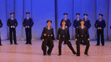 a group of men in navy uniforms are dancing on stage