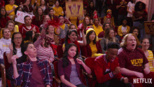 a crowd of people sitting in a theatre with a wilson shirt on