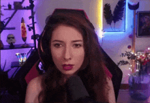 a woman is sitting in a chair in front of a microphone and looking at the camera .
