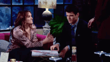 a man and a woman are sitting at a table with a menu in front of them