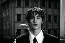 a young man in a suit and tie stands in front of a building