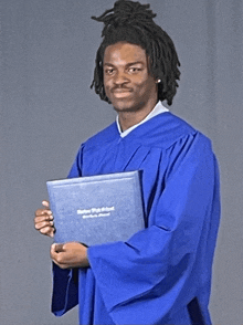 a man in a blue cap and gown is holding a diploma