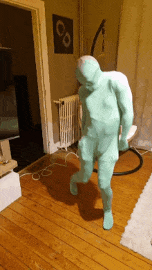 a man in a green bodysuit is standing on a wooden floor