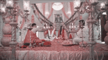 a group of people are sitting on a stage in a room with candles