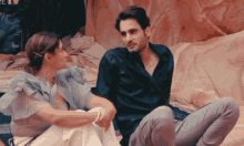 a man and a woman are sitting next to each other and the man is wearing a black shirt
