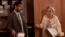 a man in a suit and tie stands next to an elderly woman in front of a wooden door that says 408