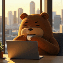 a teddy bear is sitting at a desk with a laptop and a cup of coffee