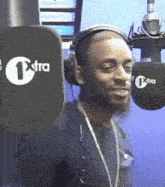 a man wearing headphones stands in front of a microphone with extra written on it