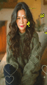 a woman wearing a green sweater with hearts around her and the letter r on her forehead