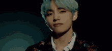 a close up of a young man with green hair wearing a necklace and a suit .