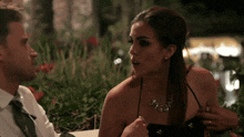 a woman in a black dress is talking to a man