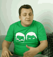 a man wearing a green t-shirt with two faces and glasses on it