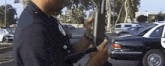 a police officer is holding a gun in front of a car