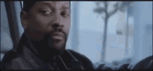 a man with a beard is sitting in a car looking out the window .