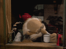 a stuffed animal wearing glasses and a hat looks out of a window