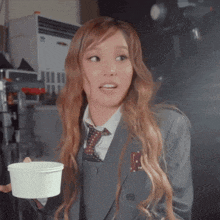 a girl in a suit and tie is holding a cup