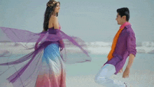 a man in a purple shirt kneeling down next to a woman in a purple dress