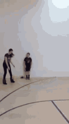 a woman is dancing on a basketball court while another woman looks on .