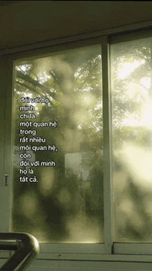 a window with a reflection of trees and a quote in a foreign language