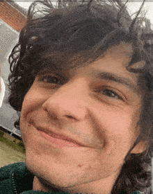 a man with curly hair and a beard is smiling