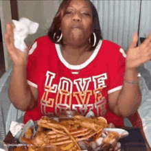 a woman in a red shirt that says love love love is eating crabs .