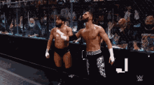two wrestlers are standing next to each other in front of a crowd with a w logo in the background