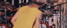 a person in a yellow shirt stands in front of a drum set that says evans on it