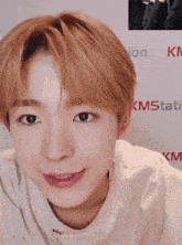 a close up of a person 's face with kmstati written on the wall behind him