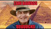 a man wearing a hat with the words " zahi hawass suuuucks " written on it
