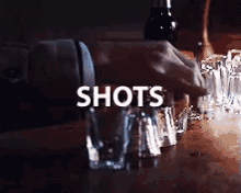 a person pouring shots into shot glasses on a table