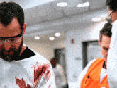 a man with blood on his shirt is wearing glasses